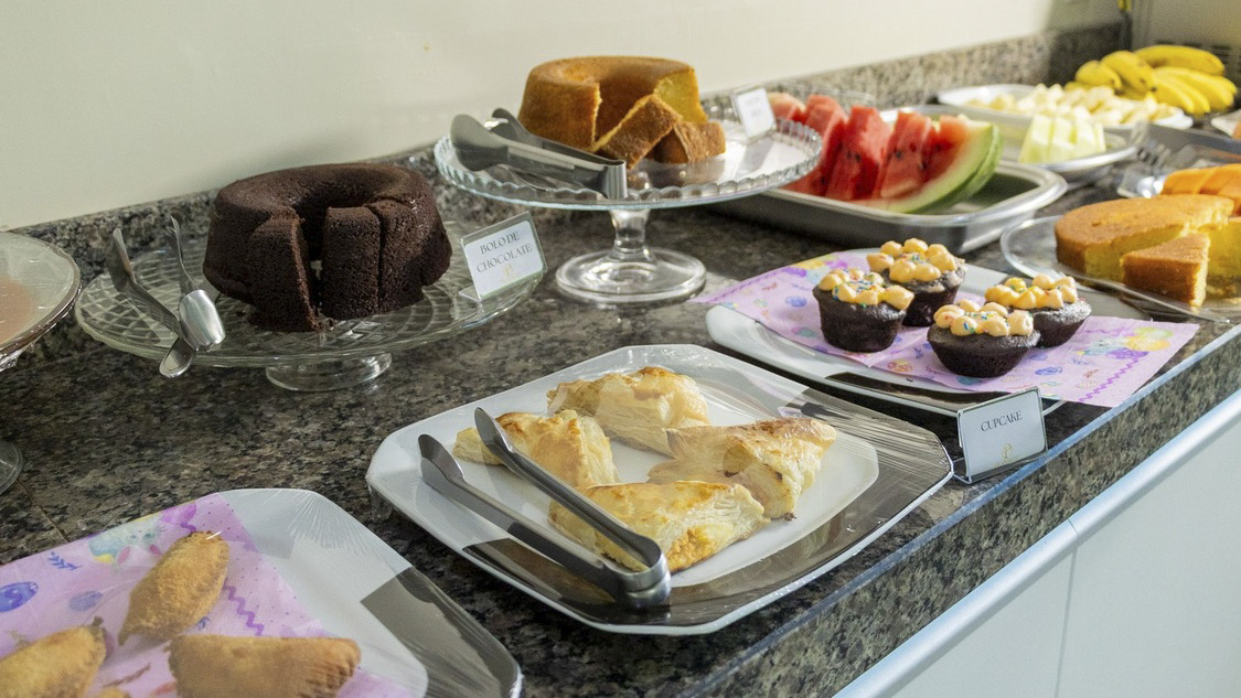 Buffet de café da manhã com bolos, frutas, salgados e folhados sobre uma bancada no Planalto Palace Hotel, em Rurópolis, Pará.
